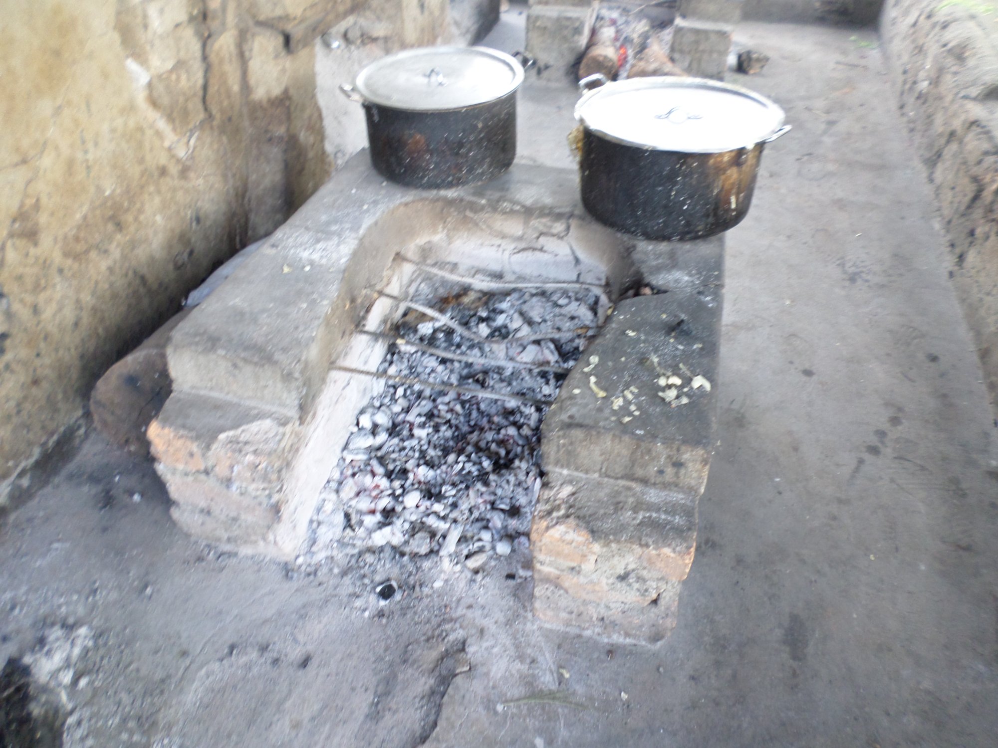 Firewood ash and cooking pots on open concrete stove